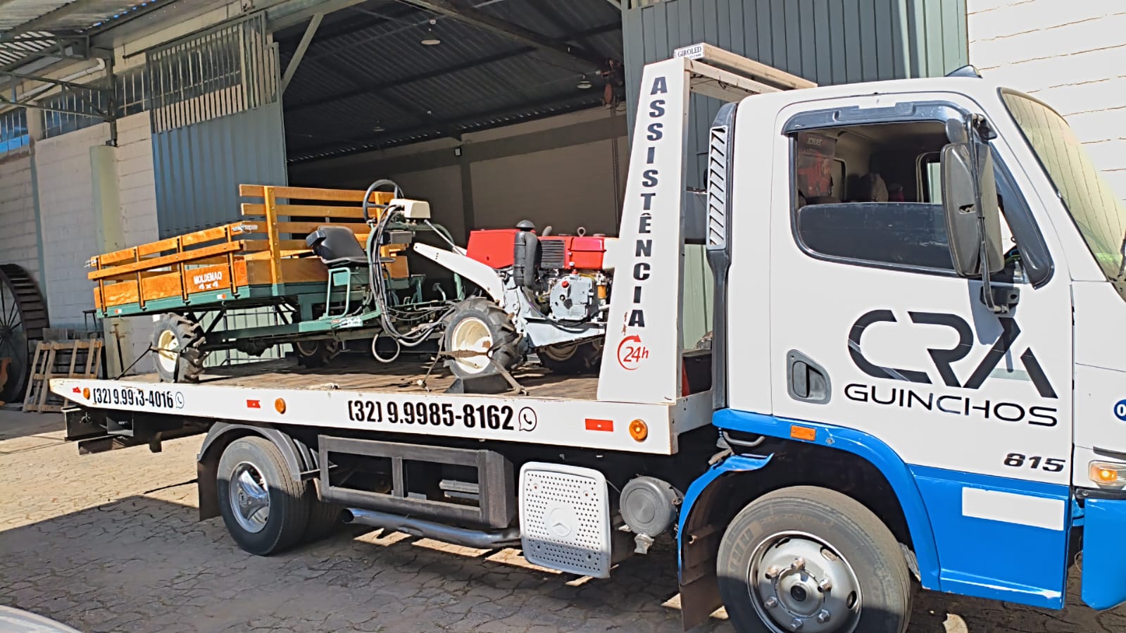 Micro trator e carreta agrícola transportados na plataforma da C.R.A Guinchos